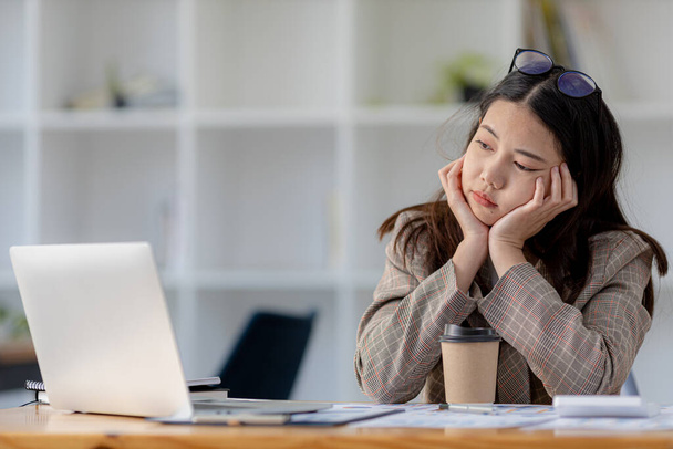 A female startup employee looks stressed from working all day, she is an accounting and finance work in a company, she is tired and stressed, she has office syndrome. Hard work concept. - Photo, Image