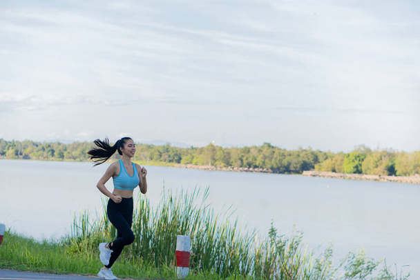 Azjatka jogging w parku, zdrowy styl życia i koncepcja sportowa. kobieta jogging w parku w świetle słonecznym w piękny letni dzień - Zdjęcie, obraz