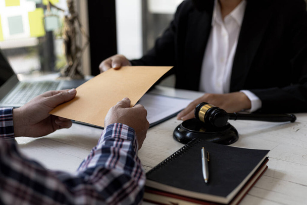 Attorneys are accepting documents from clients who come in to testify in case of embezzlement from business partners who venture into business. The concept of hiring a lawyer for legal proceedings. - Photo, Image