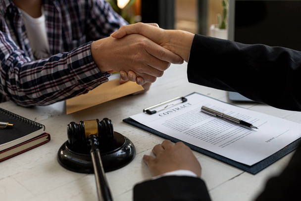 Lawyers shake hands with clients who come to testify in the case of embezzlement from business partners who jointly invest in the business. The concept of hiring a lawyer for legal proceedings. - Photo, image