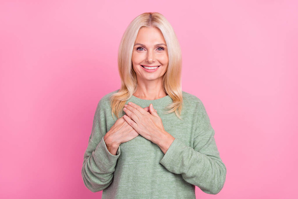 Photo of joyful aged blond lady hands brest wear grey pullover isolated over pink color background. - Foto, Imagem