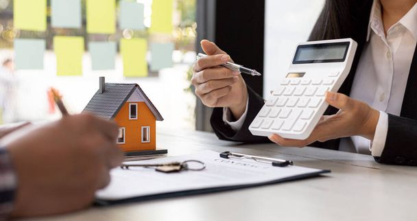 A rental company employee is calculating the cost for the customer to agree to sign a rental contract, explaining the rental terms and conditions. Home and real estate rental ideas. - Photo, Image