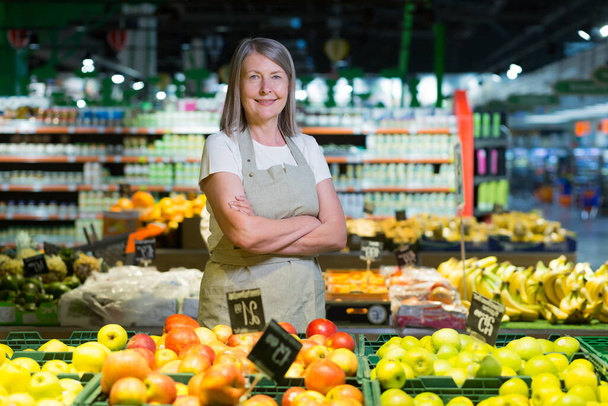 Portrait of senior woman manager of grocery store, supermarket. Standing in work clothes, arms crossed, looking at the camera, smiling - Foto, Bild