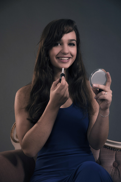 Teenage girl with long brown hair doing lipstick and holding lit - Foto, Imagen