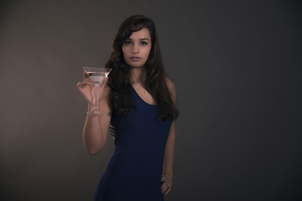 Bastante morena adolescente sosteniendo copa de cóctel vistiendo azul
 - Foto, imagen