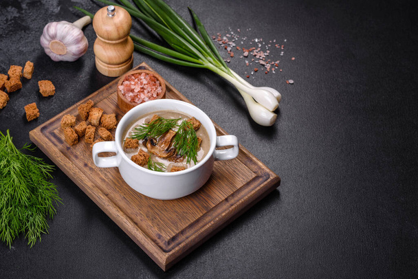A delicious fresh, thick soup of mushroom puree with breadcrumbs, spices and herbs on a wooden board against a dark concrete background. Vegetarian cuisine - Foto, Bild