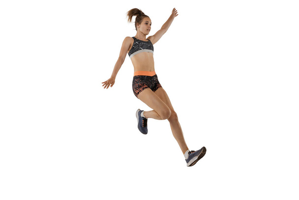 Long jump technique. Studio shot of professional female athlete in sports uniform jumping isolated on white background. Concept of sport, action, motion, speed, healthy lifestyle. Copy space for ad - 写真・画像