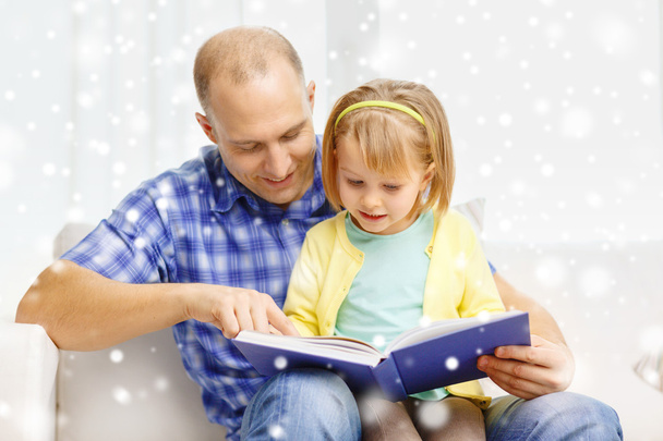 smiling father and daughter with book at home - Foto, Imagen