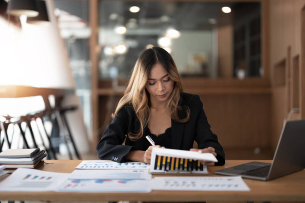 Портрейр бухгалтер азіатська жінка, що працює та аналізує фінансову звітність проектний облік з графіком та калькулятором в сучасному офісі: фінанси та бізнес-концепція
 - Фото, зображення