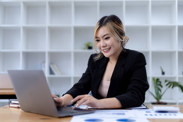 Beautiful Asian young woman looking at information on a laptop, concept image of Asian business woman working smart, modern female executive, startup business woman, business leader woman. - Foto, afbeelding