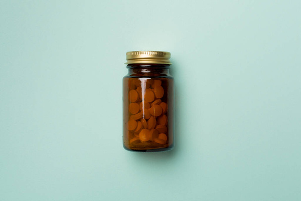 Garrafa de vidro com pílulas em fundo de cor, vista superior. - Foto, Imagem