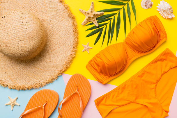 Woman swimwear and beach accessories flat lay top view on colored background Summer travel concept. bikini swimsuit, straw hat and seasheels. Copy space Top view. - Valokuva, kuva