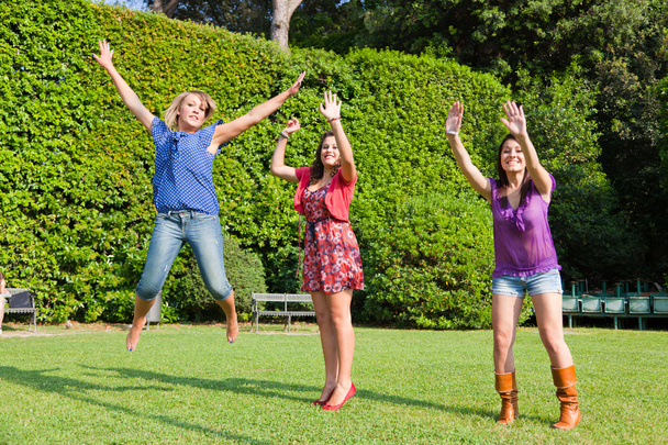 Gelukkig vrouwelijke jeugdvrienden springen - Foto, afbeelding