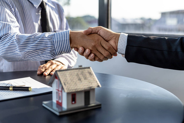The salesperson of the housing estate in the project and the customer shake hands after successfully signing the contract. Concept of selling housing estates and real estate. - Zdjęcie, obraz