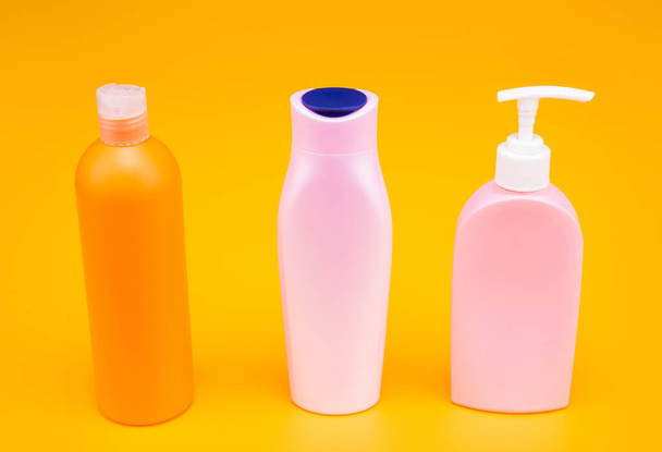 Store your shampoo, shower gel and lotion soap. Cosmetic packaging bottles in row. Refillable bottles yellow background. Liquid containers for toiletries. For bath products, copy space. - Photo, image