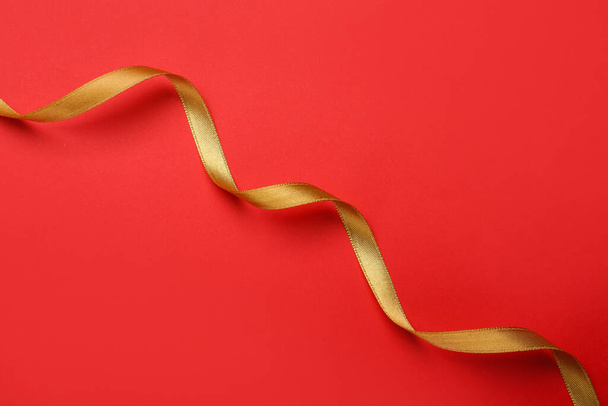 Beautiful golden ribbon on red background, top view - Foto, immagini
