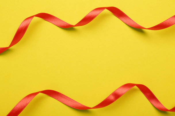 Beautiful red ribbons on yellow background, flat lay. Space for text - Valokuva, kuva