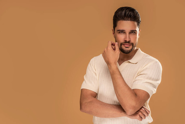 Young handsome man with beard wearing casual polo shirt, posing on studio background, looking at the camera. Beauty portrait. A lot of copy space. - Fotografie, Obrázek