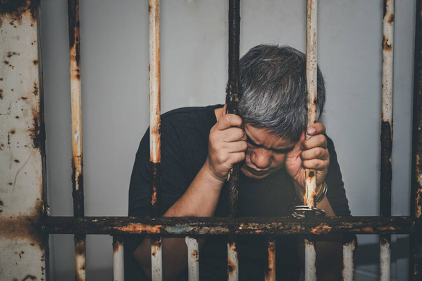 Asiatico maschio criminali è stato arrestato e ammanettato in un sporco gabbia, concetto per il colpevole è stato punito per aver infranto la legge - Foto, immagini