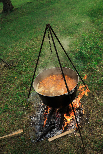 Caldero suspendido sobre el fuego, cocinando en el campo. La comida se cocina al aire libre en el fuego - Foto, Imagen