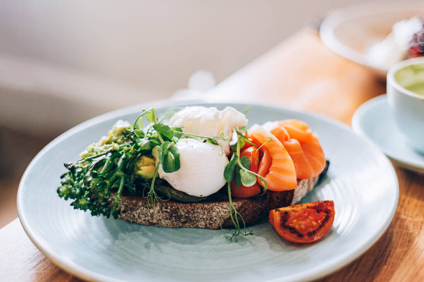 Healthy breakfast from poached eggs, steamed broccolli, salmon, smashed avocado, grilled mushrooms and tomato on toast - Valokuva, kuva