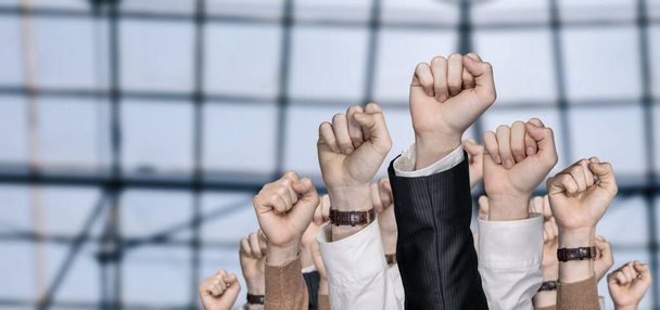 A munkahelyi tiltakozás koncepciója. Emelt kezek az emberek egy öklöt a háttérben egy panoráma ablak. - Fotó, kép
