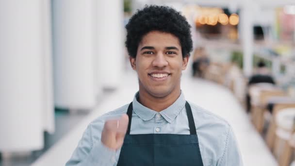 Barátságos boldog afro-amerikai férfi munkás pincér eladó kötény ember mutat jó tökéletes jel a kéz kis üzlet tulajdonosa kávézó étterem üzlet mutatja, mint hüvelykujj felfelé néz a kamerába. Magas - Felvétel, videó