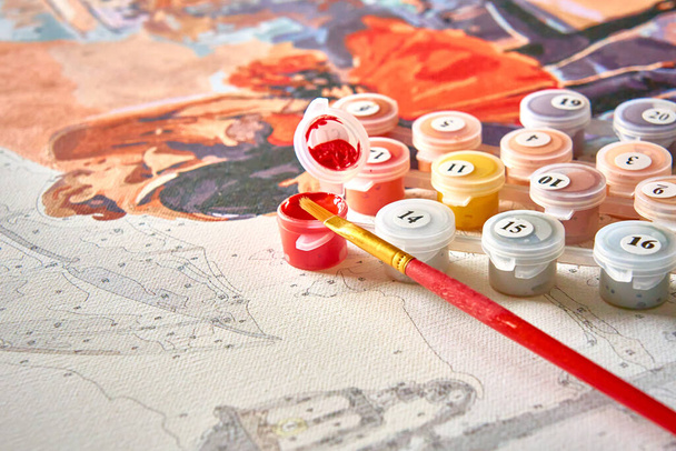 Painting for beginners. A set of numbered acrylic paints, a brush and a canvas with numbers for painting a painting by numbers. Self-isolation, creative leisure. - Photo, Image