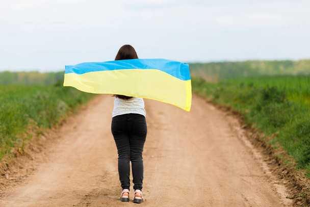 Woman with Ukrainian flag in wheat field.Happy woman celebrating Independence Day. - Foto, Imagem