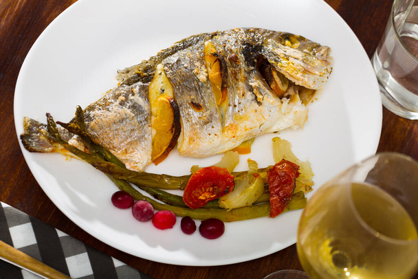 Sea bream baked in oven served with asparagus, onion and tomatoes - Foto, Imagen