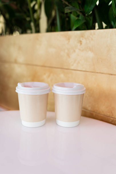 Twee papieren koffiekopjes in een café, koffie om mee te nemen concept. Wandelingen in de open lucht - Foto, afbeelding