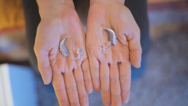 Showing modern hearing aids on both hands - Materiał filmowy, wideo