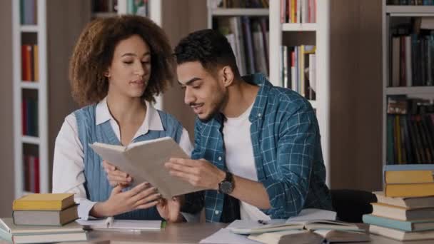 女子大生と議論する若い男を勉強するための試験の準備を大学図書館に座っている2人の多様な学生感情的な一緒に宿題を読んで教科書高等教育の概念 - 映像、動画