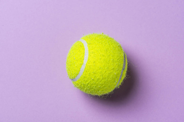 Yellow tennis ball on a purple table.. - Foto, afbeelding