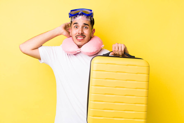 young hispanic man feeling stressed, anxious or scared, with hands on head. travel concept - 写真・画像