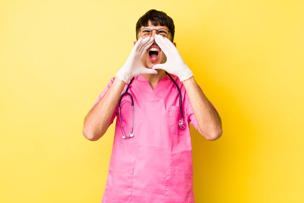young hispanic man feeling happy,giving a big shout out with hands next to mouth. veterinarian concept - Foto, Imagem