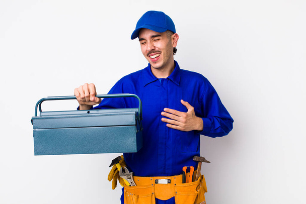 young hispanic plumber laughing out loud at some hilarious joke. toolbox concept - Zdjęcie, obraz
