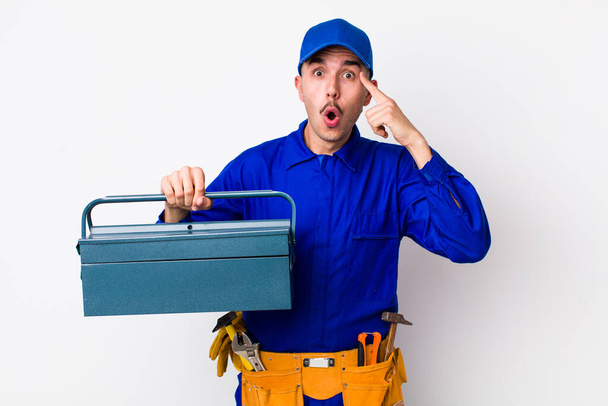 young hispanic plumber looking surprised, realizing a new thought, idea or concept. toolbox concept - Fotoğraf, Görsel