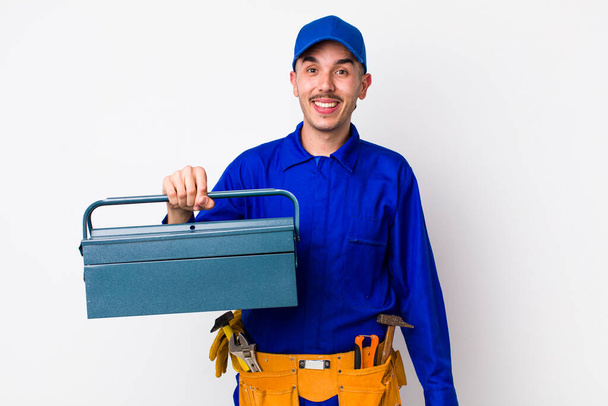 young hispanic plumber looking happy and pleasantly surprised. toolbox concept - Zdjęcie, obraz