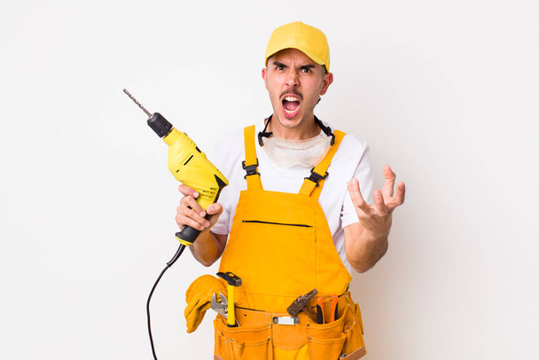 hispanic handyman looking angry, annoyed and frustrated. drill concept - Φωτογραφία, εικόνα