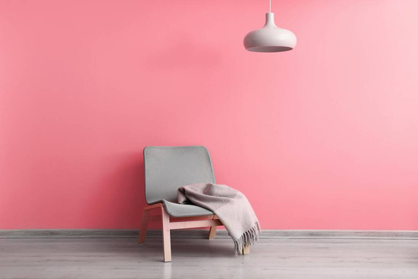 Comoda poltrona con plaid vicino alla parete rosa - Foto, immagini
