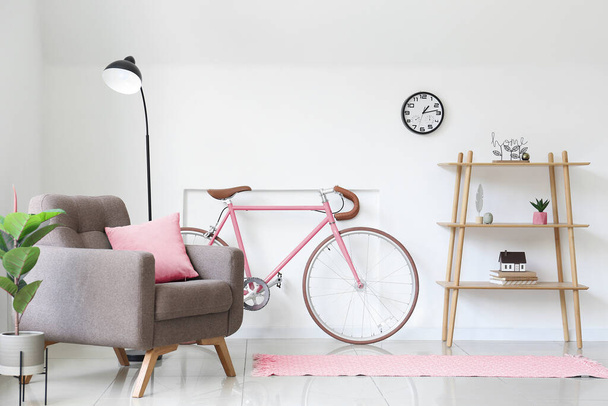 Интерьер светлой гостиной с креслом, полками и велосипедом - Фото, изображение