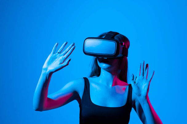Young woman working in VR goggles on a grey background. Modern architect using virtual reality glasses at workplace. Designer working in augmented reality vr studio - Foto, Imagen