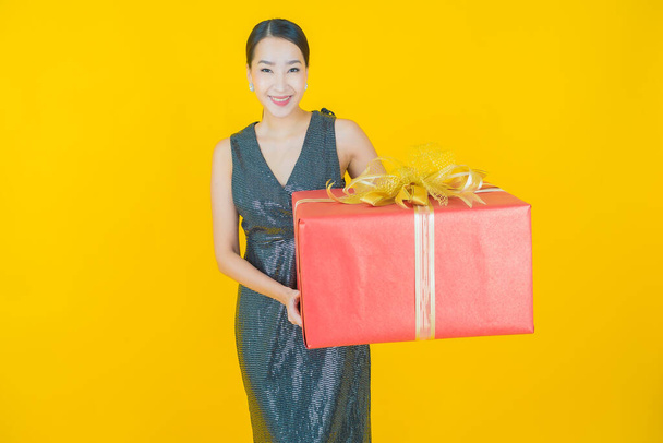 Πορτρέτο όμορφη νεαρή ασιατική γυναίκα χαμόγελο με κόκκινο κουτί δώρου στο φόντο χρώμα - Φωτογραφία, εικόνα