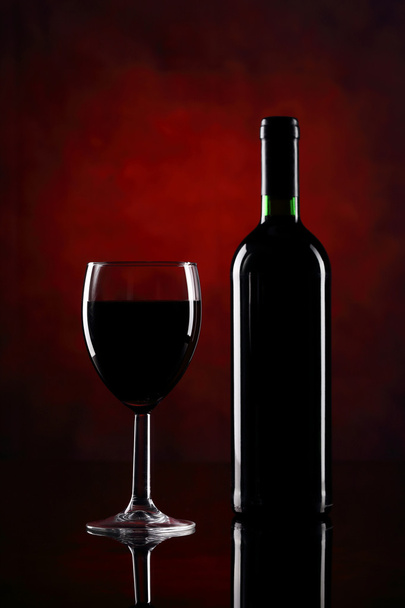 Red wine glass with bottle on the red background - Foto, Imagen