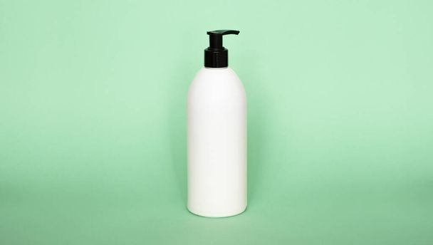 White plastic bottle with shampoo, conditioner or shower gel on a green background. Mock up template for design - Foto, imagen