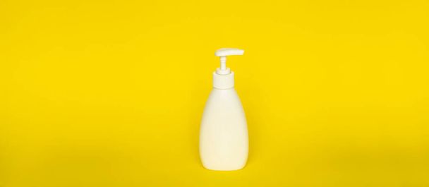 Large white plastic bottle with pump dispenser on yellow background. Mock up template for design - Foto, Imagem