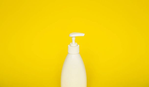 Liquid container for gel, lotion, cream, shampoo, bath foam on yellow background. Cosmetic plastic bottle with white dispenser pump. Mock up template for design - Φωτογραφία, εικόνα