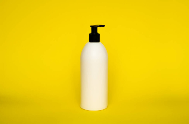 Large white plastic bottle with pump dispenser on yellow background. Mock up template for design - Foto, afbeelding