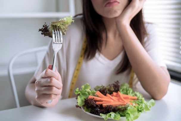 A boldogtalan ázsiai nők fogyókúráznak, és a villán nézik a zöldségeket.. - Fotó, kép